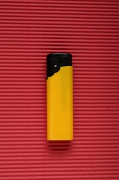Photo of Stylish small pocket lighter on red corrugated fiberboard, top view