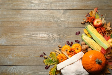 Flat lay composition with vegetables, berries and autumn leaves on wooden table, space for text. Thanksgiving Day