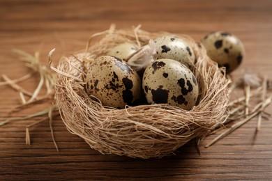 Nest with quail eggs on wooden table, closeup