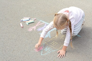 Photo of Little child drawing happy family with chalk on asphalt