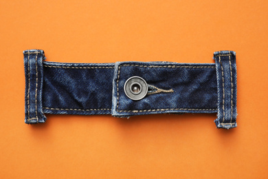 Garment accessory and cutting details for jeans on orange background, flat lay