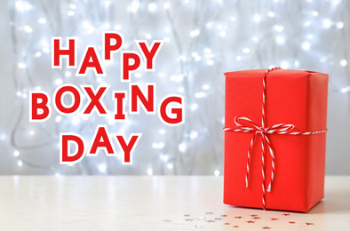 Text Happy Boxing Day near gift against blurred lights