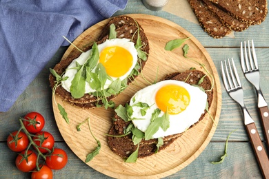 Delicious sandwiches with arugula and fried egg on blue wooden table, flat lay