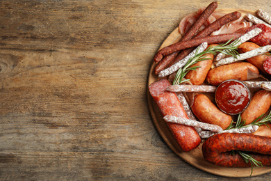 Different types of sausages with rosemary served on wooden table, top view. Space for text