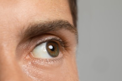 Photo of Handsome adult man against grey background, closeup of eye, space for text