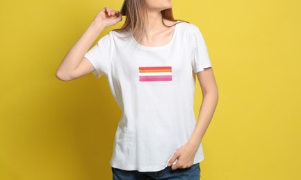 Young woman wearing white t-shirt with lesbian flag on yellow background. LGBT concept
