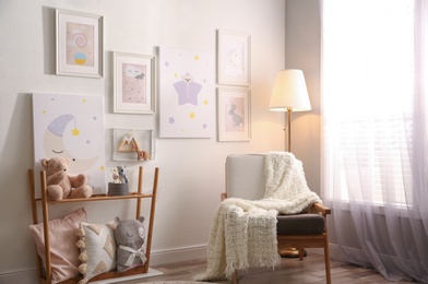 Stylish child's room interior with comfortable armchair and beautiful pictures