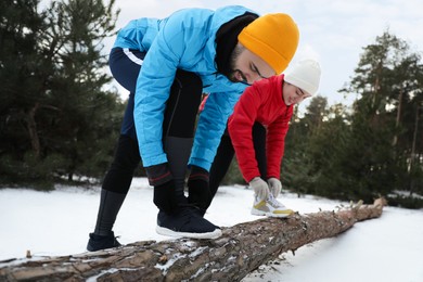 People lacing sneakers on log in winter forest. Outdoors sports exercises