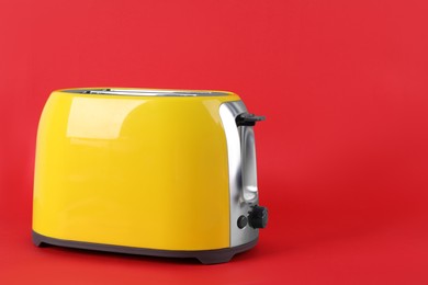 Photo of Modern toaster on red background, space for text. Household equipment