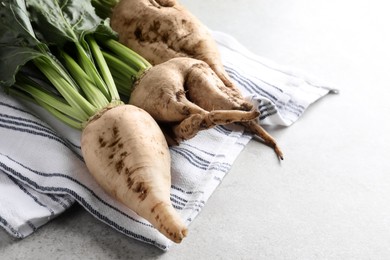 Photo of Fresh sugar beets with leaves on light grey table, closeup