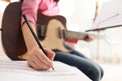 Child with guitar writing music notes at home, closeup