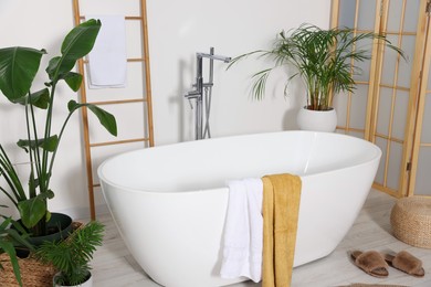 Stylish bathroom interior with modern ceramic tub and beautiful houseplants