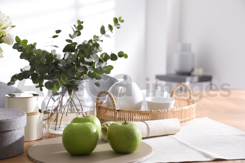 Photo of Apples and tea set on wooden table indoors. Stylish interior design