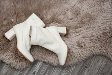 Pair of stylish leather shoes on faux fur, flat lay. Space for text