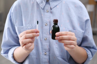 Woman holding bottle of brilliant green and cotton bud, closeup