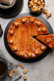 Photo of Sliced delicious caramel cheesecake with popcorn served on light grey table, flat lay