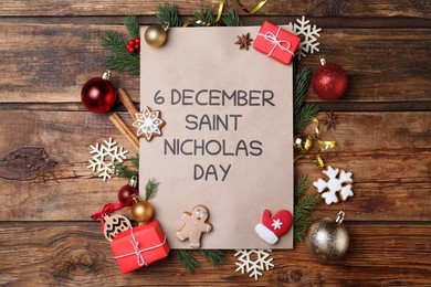 Photo of Card with text 6 December Saint Nicholas Day and festive decor on wooden table, flat lay