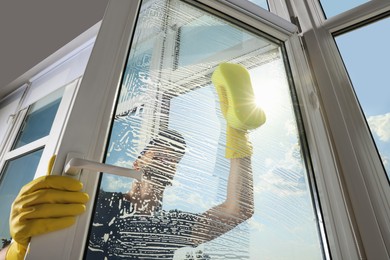 Man cleaning glass with sponge indoors, low angle view