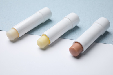 Different hygienic lipsticks on color background, closeup