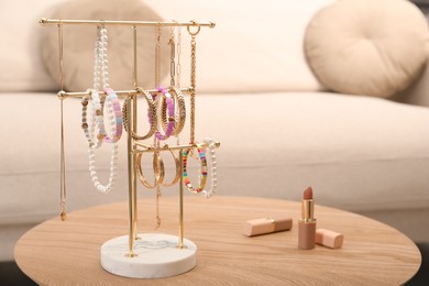 Holder with set of luxurious jewelry on wooden table in living room