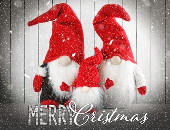 Image of Merry Christmas! Cute gnomes on table against white wooden background