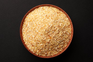 Bowl of dehydrated garlic granules on black background, top view