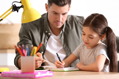 Man helping his daughter with homework at table indoors
