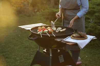 Woman cooking vegetables on barbecue grill outdoors, closeup
