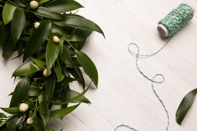 Beautiful handmade mistletoe wreath and thread spool on white wooden table. Traditional Christmas decor
