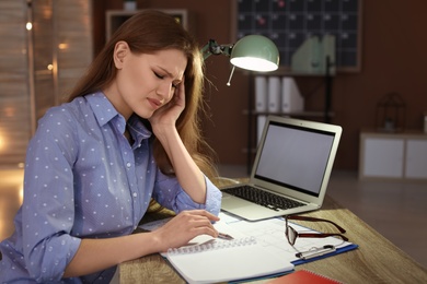 Overworked young woman with headache in office