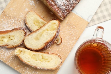 Photo of Pieces of delicious yeast dough cake and tea on white table, flat lay
