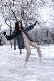 Young woman falling on slippery icy pavement in park
