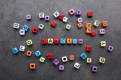 Word Calcium made of colorful plastic beads with letters on black background, top view