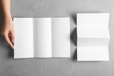 Woman with blank brochures on grey background, top view. Mockup for design