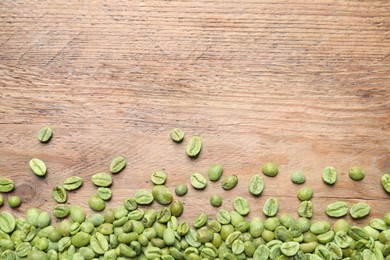 Many green coffee beans on wooden table, flat lay. Space for text