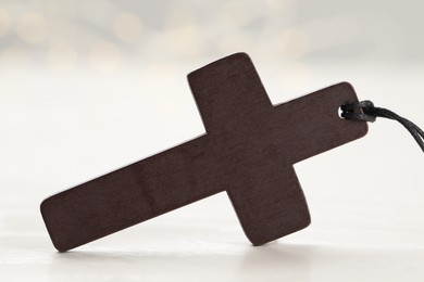 Christian cross on white wooden table, closeup