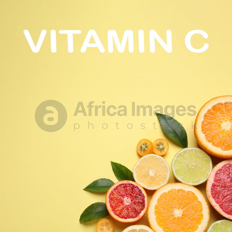 Source of Vitamin C. Fresh juicy citrus fruits with green leaves on light yellow background, flat lay