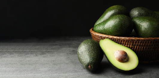 Ripe avocados on grey table against dark background, space for text. Banner design
