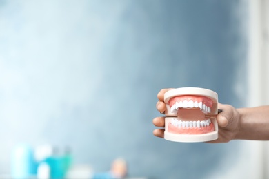 Dentist holding educational model of oral cavity with teeth in clinic, closeup. Space for text