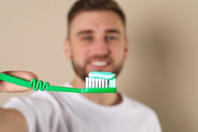 Young man with brush and toothpaste on color background, selective focus. Teeth care