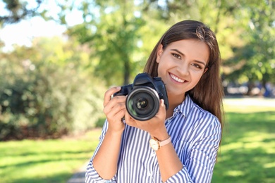 Young female photographer with professional camera in park