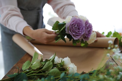Florist making beautiful wedding bouquet at wooden table, closeup