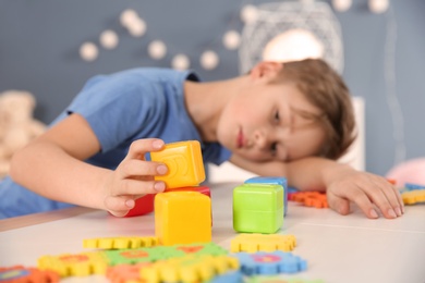 Little boy with autistic disorder playing at home, closeup of cubes