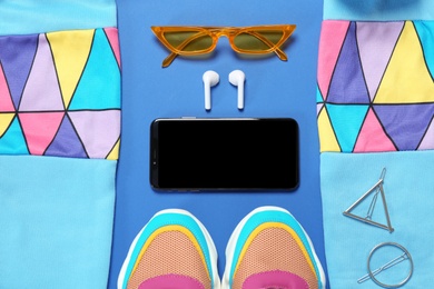 Photo of Flat lay composition with stylish sportswear and smartphone on blue background
