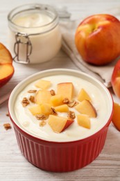 Delicious yogurt with fresh peach and granola on white wooden table
