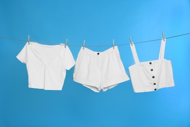 Photo of Different clothes drying on laundry line against light blue background
