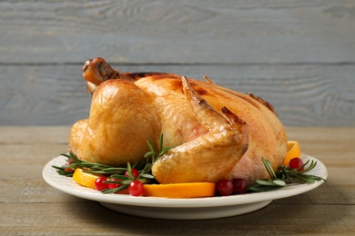 Delicious cooked turkey served with rosemary, oranges and cranberries on wooden table. Thanksgiving Day celebration