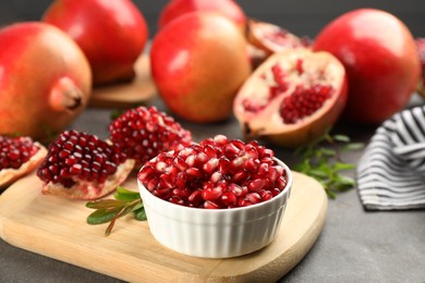 Delicious ripe pomegranate kernels in bowl on grey table, closeup