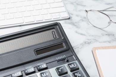 Calculator, keyboard and glasses on white marble table, closeup. Tax accounting