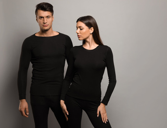 Couple wearing thermal underwear on grey background. Space for text